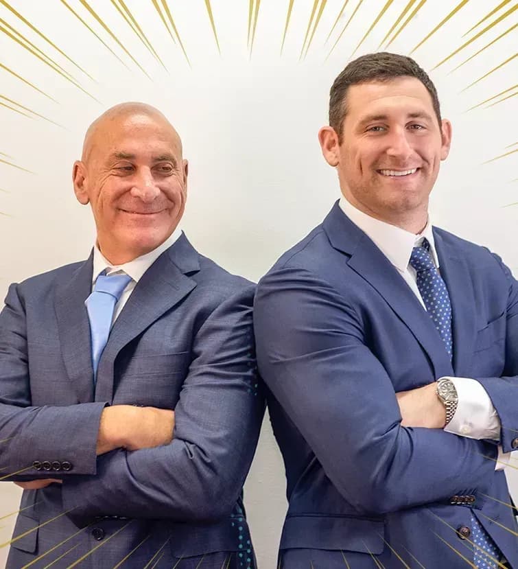  Scott and Alex Senft from Senft Legal personal injury law firm, standing back to back and smiling with arms crossed.
