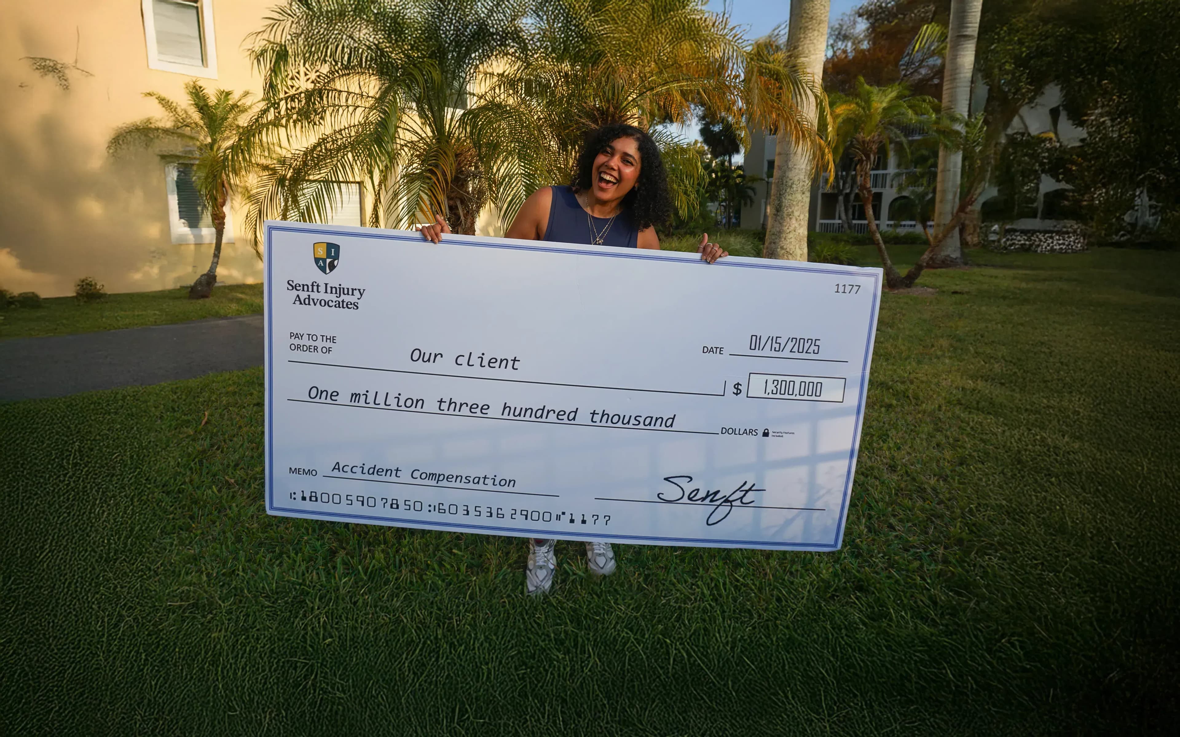 Client holding large check of one million three hundred thousand dollar from her car accident compensation claim with senft injury advocates personal injury law firm.
