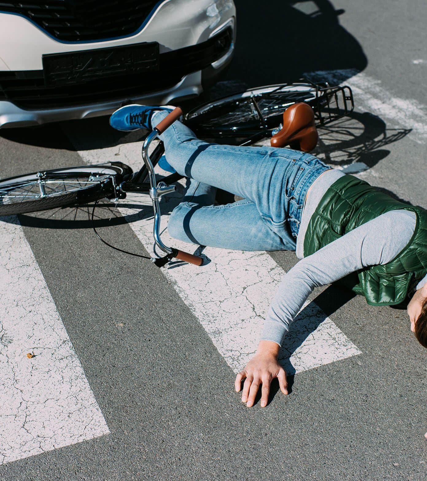 A cyclist prone on the crosswalk after being struck by a car in a bicycle accident.